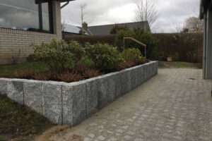 Helhedsskabende fornyelse af belægningsarealer, indkørsel og have. Indkørslen er belagt med SF-coloc sten. Velkomstbedet med surbundsplanter er etableret for at løse niveauforskellen mellem indkørsel og den resterende grund